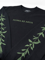 A black long-sleeve crewneck sweatshirt featuring the text 'ALOHA KE AKUA' printed in sage green across the chest, with matching green maile running down both sleeves.