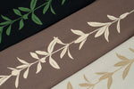 Maile longsleeve tees. A dark green print on black, a cream print on coco-brown, and a tan print on off-white or dust colored tees.