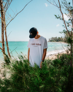 E Pule Kākou (Let Us Pray) tee White with Red Text at the Beach